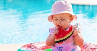 a baby eating watermelon in a pool